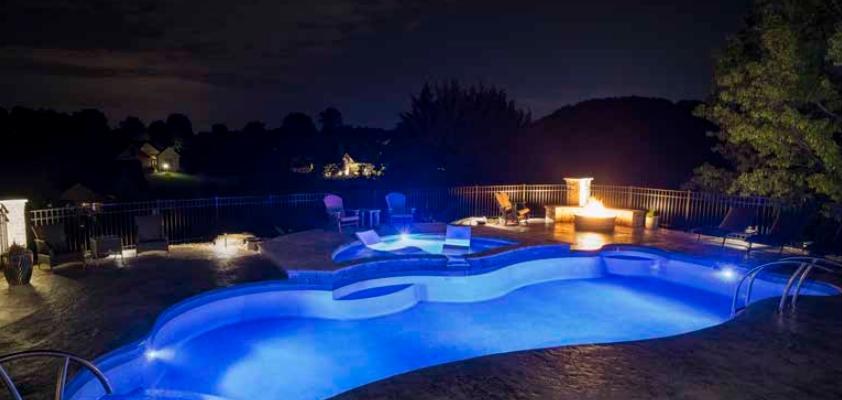 Freeform Latham pool glowing with blue LED lighting at night